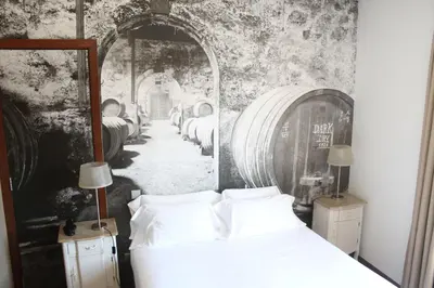 a bedroom with a bed and a painting of a wine cellar at Oca Ribeira do Porto Hotel in Porto