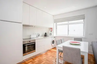 a kitchen with white cabinets and a table with chairs at Liiiving in Porto - Sunny Santa Catarina in Porto