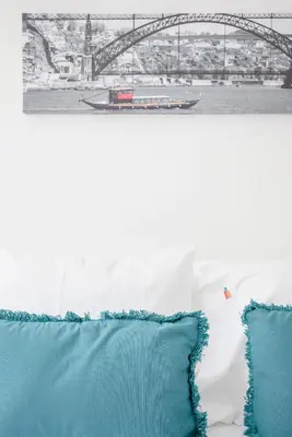 a bed with blue pillows and a bridge in the background at Liiiving in Porto - Sunny Santa Catarina in Porto
