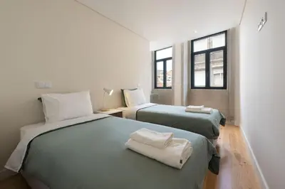 two beds in a room with two windows at BmyGuest - São Vitor Balcony Apartment in Porto