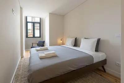 a bedroom with a large bed with two towels on it at BmyGuest - São Vitor Balcony Apartment in Porto
