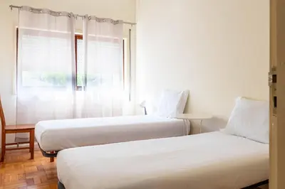 two beds in a room with a window at Convenient 3-Bedroom Apartments next to Bom Sucesso in Porto