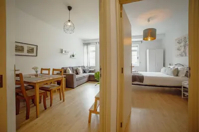 a living room with a dining room table and a bedroom at Alegria Flat City Center with Elevator by Vacationy in Porto