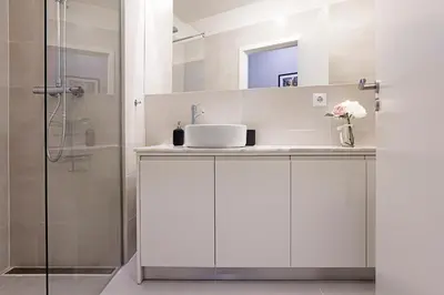 a white bathroom with a sink and a shower at Turquoise Central Flat w AC & Balcony by LovelyStay in Porto