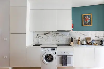 a white kitchen with a washing machine in it at Turquoise Central Flat w AC & Balcony by LovelyStay in Porto