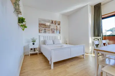 a white bedroom with a bed and a table at Travel and Live Faria Guimarães in Porto