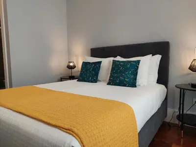 a bedroom with a large bed with a yellow blanket at Cool Suites in Porto