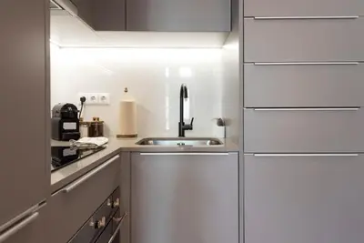 a kitchen with white cabinets and a sink at Tripas-Coração, Almada Charming City Center in Porto
