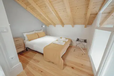 a small bedroom with a bed and a wooden ceiling at Downtown Clerigos Duplex With River View by Vacationy in Porto