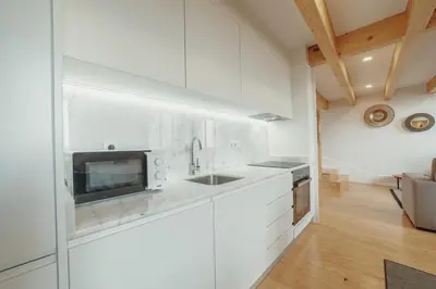 a white kitchen with a sink and a microwave at Downtown Clerigos Duplex With River View by Vacationy in Porto