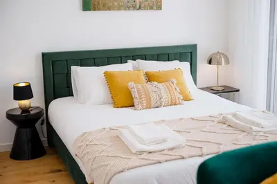 a large bed with yellow pillows and a green headboard at Chimney Luxury House with AC in Porto