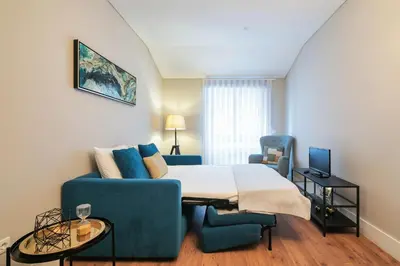 a bedroom with a bed and a blue couch at Virtudes Flat in Porto