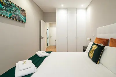 a bedroom with a large white bed with towels on it at Virtudes Flat in Porto