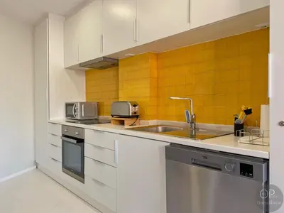 a kitchen with white cabinets and yellow tiles at 115 OPorto Guest House in Porto