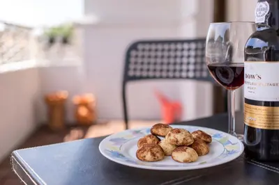 a plate of meatballs next to a glass of wine at Metro Lapa House with sunny balcony and A/C in Porto