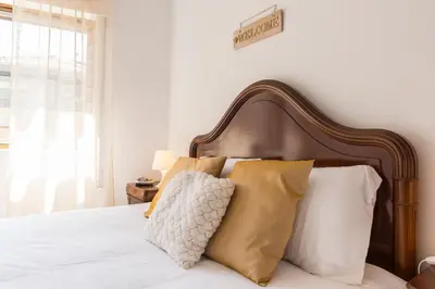 a bedroom with a bed with a wooden headboard and pillows at Metro Lapa House with sunny balcony and A/C in Porto