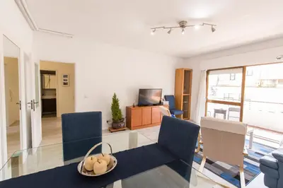 a living room with a glass table and blue chairs at Metro Lapa House with sunny balcony and A/C in Porto