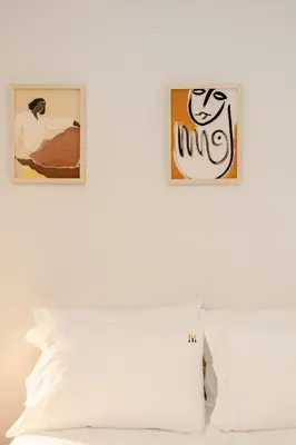 two pictures on a wall above a bed with a pillow at Liiiving in Porto - Downtown Secret Terrace in Porto