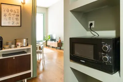 a kitchen and a living room with a microwave at Oporto family apartment in Porto