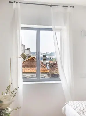 a bedroom with a window with white curtains at S. Lázaro Studio in Porto