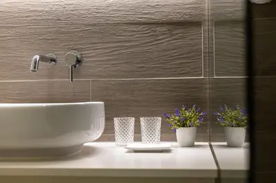a bathroom with a sink and some flowers on a counter at S. Lázaro Studio in Porto