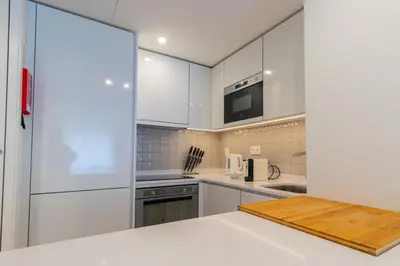 a kitchen with white cabinets and a wooden cutting board at Stunning Apartment w/ Free Parking by LovelyStay in Porto
