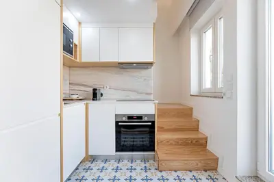 a small kitchen with white cabinets and a blue tile floor at Urban House by LovelyStay in Porto