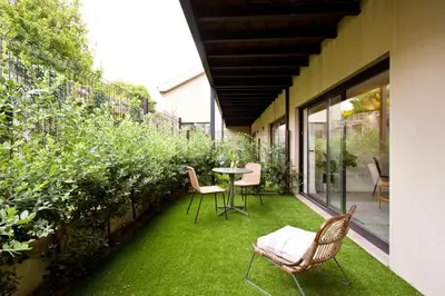 a patio with a table and chairs and green grass at Zen Garden Studio B in Porto