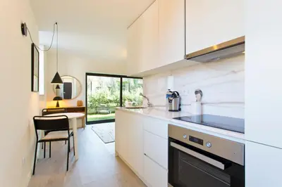 a kitchen with white cabinets and a sink and a table at Zen Garden Studio A in Porto