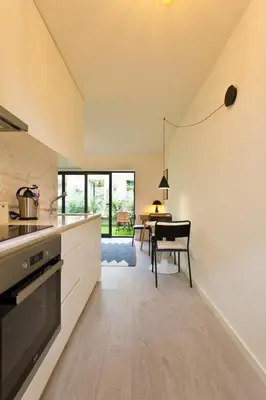 a kitchen with white cabinets and a dining table at Zen Garden Studio D in Porto
