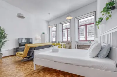 a bedroom with a large white bed and a desk at Travel & Live Alegria 248 in Porto