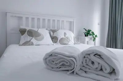 a bed with white sheets and pillows with towels on it at Travel & Live Alegria 248 in Porto
