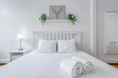 a white bedroom with a white bed with towels on it at Travel & Live Alegria 248 in Porto