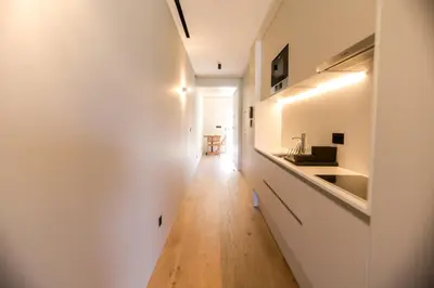 a hallway leading to a kitchen with white walls and a wooden floor at Alegria Suítes By Porto City Hosts in Porto