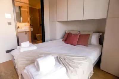 a bedroom with a large bed with white sheets and red pillows at Alegria Suítes By Porto City Hosts in Porto