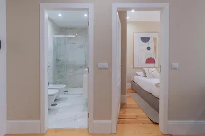 a white bedroom with a bed and a bathroom at Almada 1.3 by LovelyStay in Porto