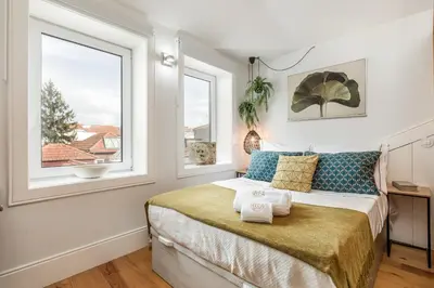 a bedroom with a bed and two windows at OPO Alegria 119 in Porto
