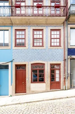 a building with red doors and windows on a street at VIVA Trindade Downtown in Porto