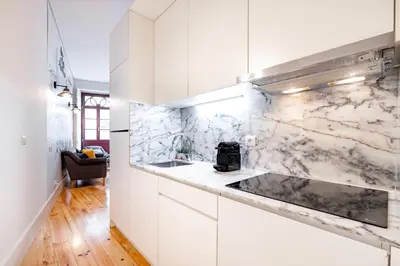 a kitchen with white cabinets and marble walls at VIVA Trindade Downtown in Porto