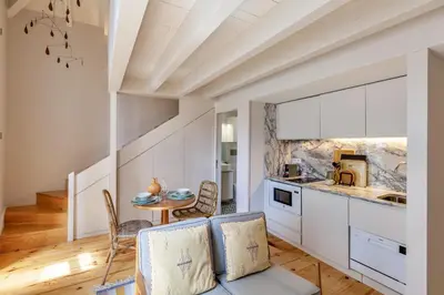 a kitchen with white cabinets and a table and chairs at D&S - JB Apartments in Porto