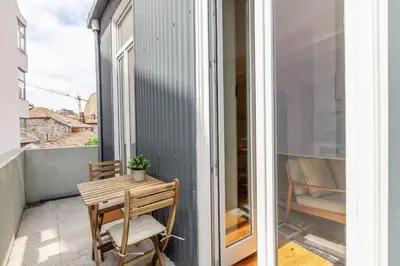 a small balcony with a wooden table and a chair at D&S - JB Apartments in Porto