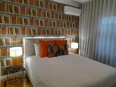a bedroom with a bed and a wall of books at Cozy Central 3 Bedrooms Bragas in Porto