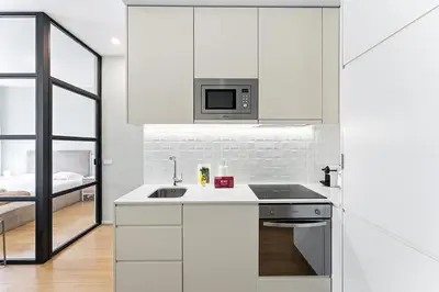 a white kitchen with a sink and a microwave at GuestReady - Modern Apartment in Bolhão in Porto