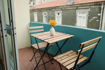 a table and two chairs and a vase with flowers on a balcony at Sunny and Spacious House, 4BD 3Bath Downtown Porto in Porto