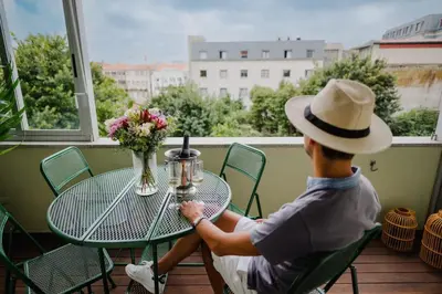 a man sitting at a table on a balcony at Sunny and Spacious House, 4BD 3Bath Downtown Porto in Porto