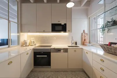 a kitchen with white cabinets and a stove top oven at Mouzinho Luxury 3BR Flat l 5 min Walk to Ribeira by Lovelystay in Porto