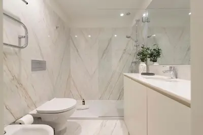 a white bathroom with a toilet and a sink at Mouzinho Luxury 3BR Flat l 5 min Walk to Ribeira by Lovelystay in Porto