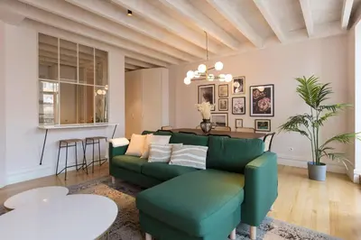 a living room with a green couch and a table at Mouzinho Luxury 3BR Flat l 5 min Walk to Ribeira by Lovelystay in Porto