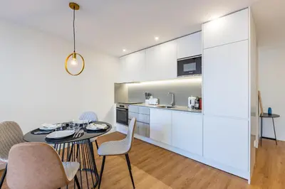 a kitchen with white cabinets and a table and chairs at Pestana Apartments - Premium in Porto