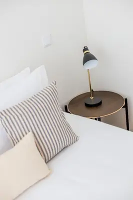 a bed with a table with a lamp and a pillow at Pestana Apartments - Premium in Porto